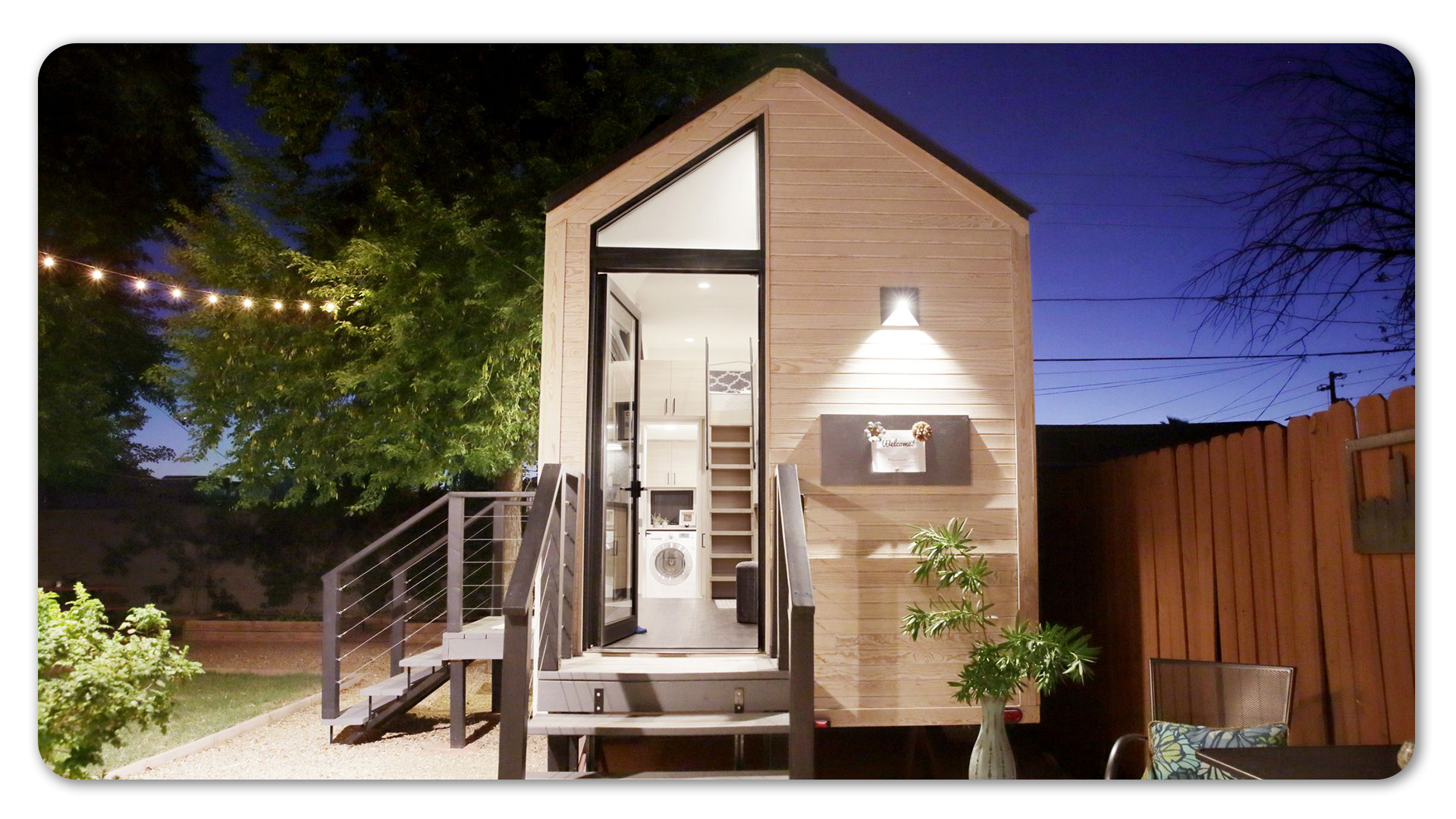 Photo of tiny home at night, all lights shining, white interior